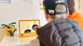 Kind schaut lachend in einen Spiegel