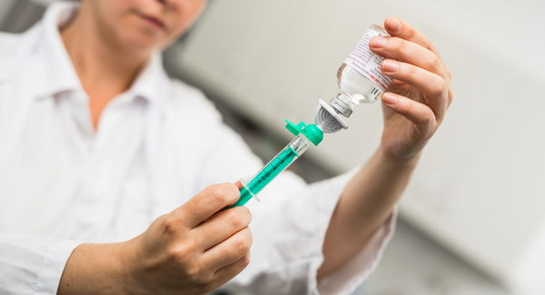 Ärztin zieht Spritze an kleinem Fläschchen auf